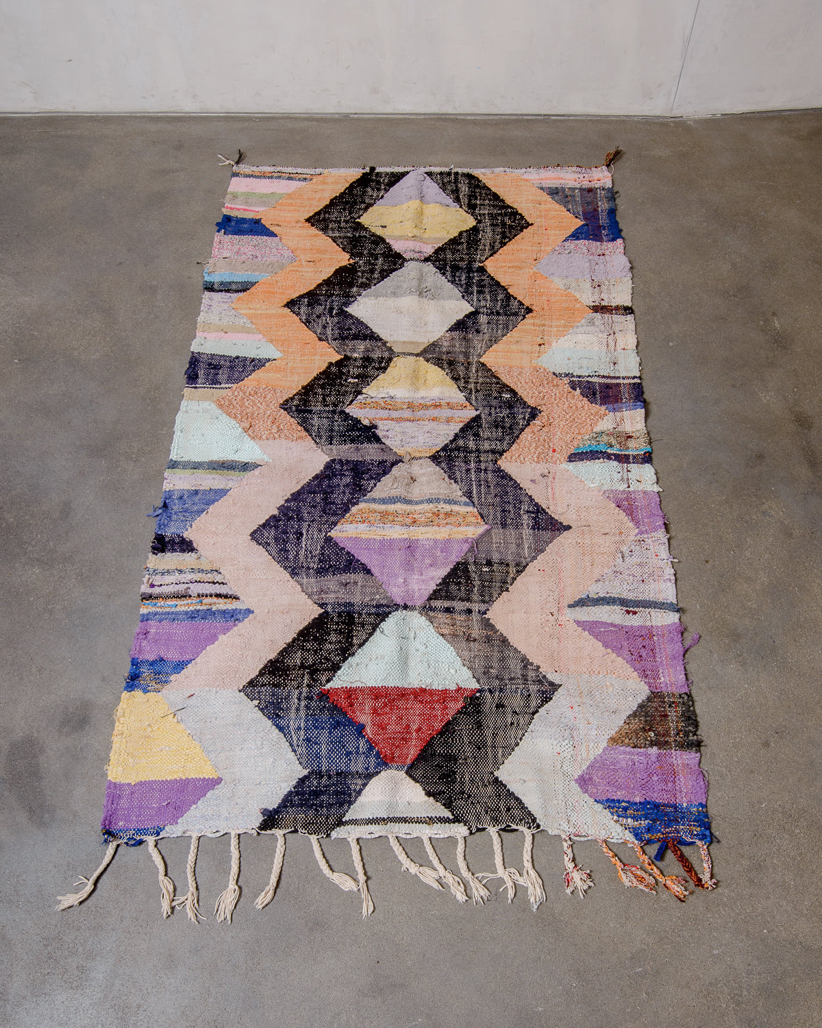 Berberlin vintage kelim rug made of recycled materials laying flat on a concrete floor.